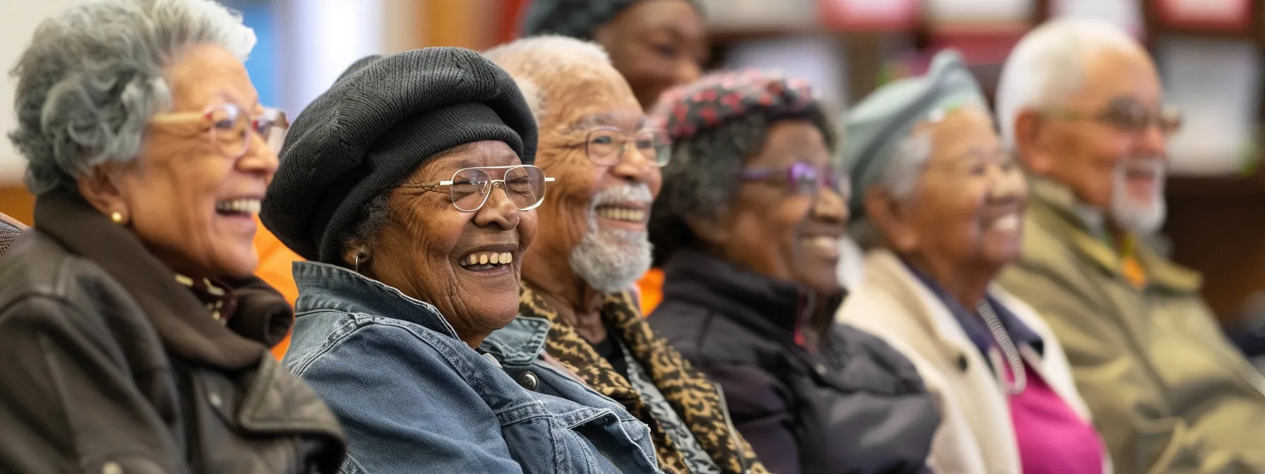 a diverse group of senior citizens smiling and discussing medicare plan options at a community center.